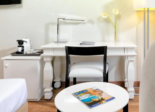 a white desk with a chair and a table with a book at H10 Salauris Palace in Salou