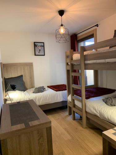 a room with two bunk beds and a table at LE RIDGE nouvelle résidence prestige - Les Arcs Paradiski in Bourg-Saint-Maurice