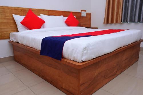 a bedroom with a large bed with red and blue pillows at Hotel Stay Shine in Mysore