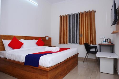 Hotel Stay Shine في ميسور: غرفة نوم مع سرير مع الوسائد الحمراء والزرقاء