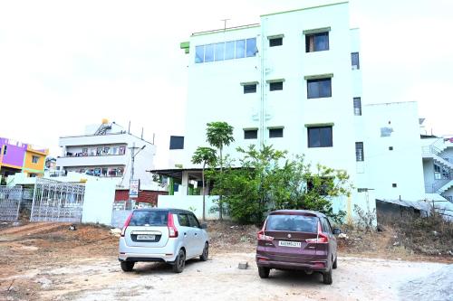 two small cars parked in front of a building at Hotel Stay Shine in Mysore
