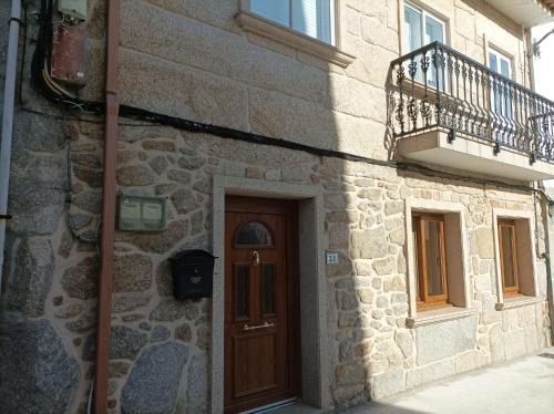 - un bâtiment en pierre avec une porte en bois et un balcon dans l'établissement Apartamento O Vento, à O Grove