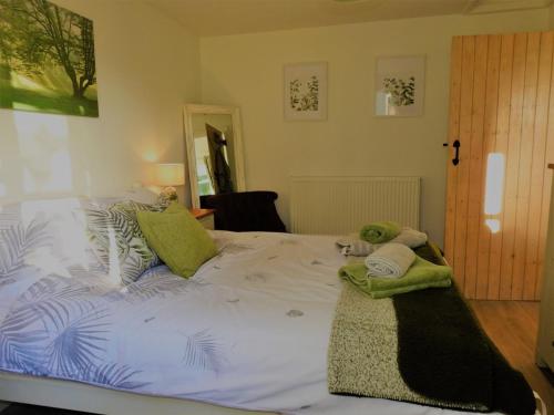 a large white bed with two stuffed animals on it at Cosy country cottage with outdoor bathing in Halkyn