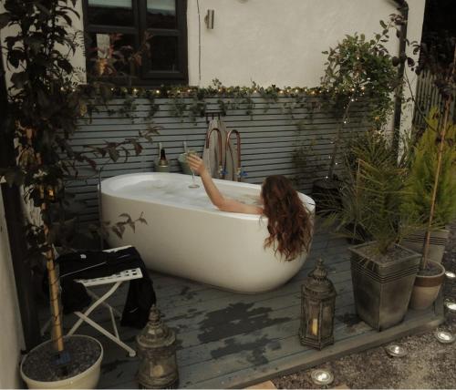 a woman is in a bath tub in a bathroom at Cosy country cottage with outdoor bathing in Halkyn