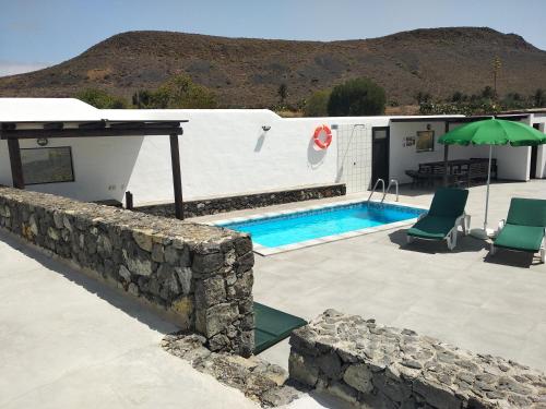 a house with a pool and a table and chairs at Finca La Tabaiba Apartamento alto in Máguez