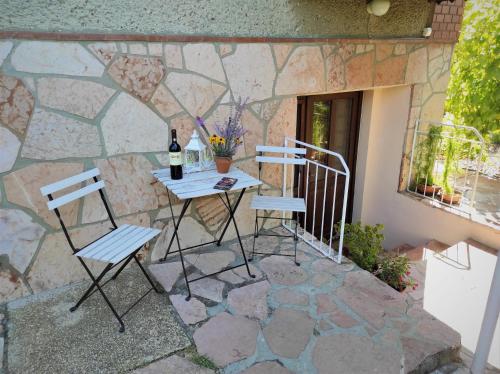 un patio con 2 sillas y una mesa con una botella de vino en Kerti lak, en Mór