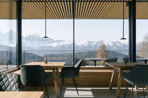 a restaurant with tables and chairs and a large window at anders mountain suites 1 in Brixen