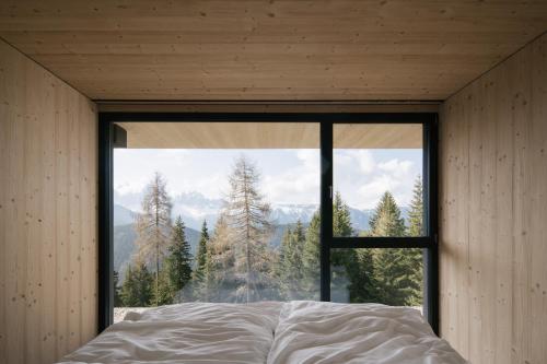 a bedroom with a large window looking out at the mountains at anders mountain suites 2 in Brixen