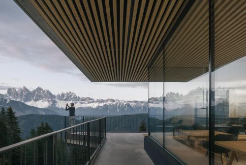 a person standing on a balcony looking out at the mountains at anders mountain suites 4 in Brixen