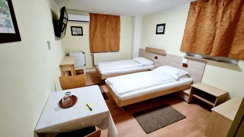 um pequeno quarto com duas camas e uma mesa em Pensiunea Zodiac em Timisoara