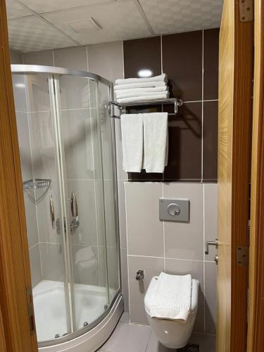 a bathroom with a shower and a toilet and towels at Demosan City Hotel in Konya