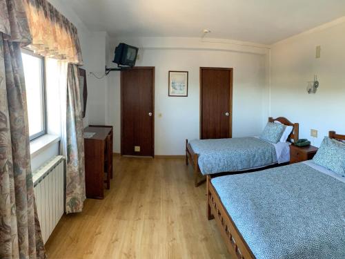 um quarto de hotel com duas camas e uma janela em Hotel Mateus em Fátima