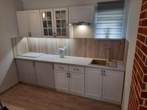 uma cozinha com armários brancos e um lavatório em apartament typu agro z tarasem em Milicz