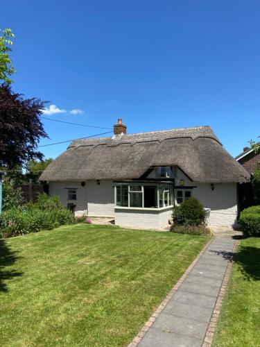 a thatch roofed house with a grass yard at Thatch Cottage, East Boldre nr Beaulieu and Lymington in Brockenhurst