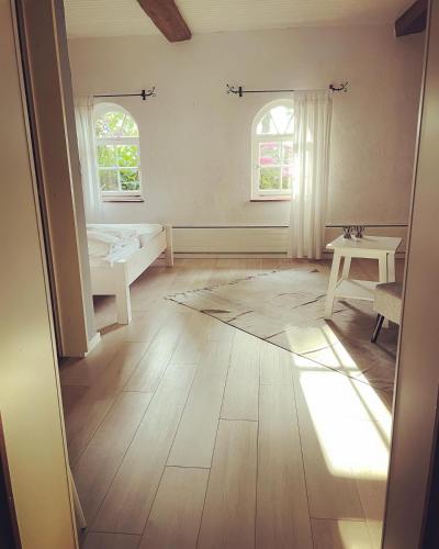 a room with a bed and a table and two windows at Hotel Gut Schöneworth in Freiburg - Elbe