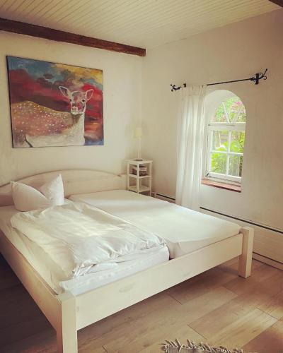 a bedroom with a white bed with a deer painting on the wall at Hotel Gut Schöneworth in Freiburg - Elbe