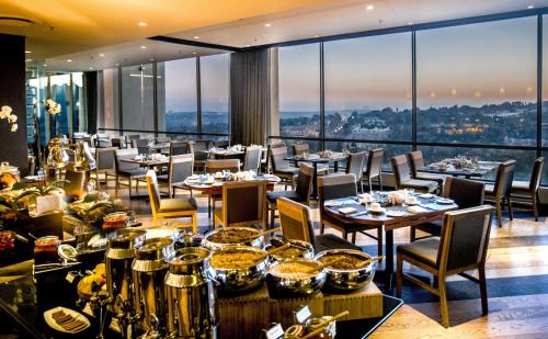 a restaurant with tables and chairs with a view at Southern Sun Hyde Park Sandton in Johannesburg