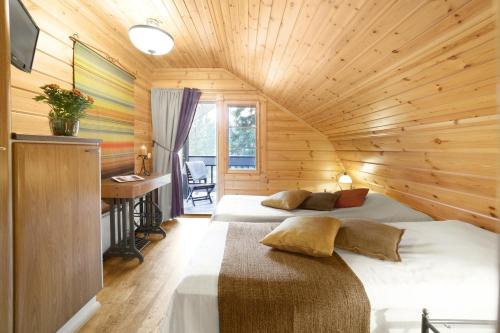 a bedroom with two beds in a wooden cabin at Vuokatin Aateli Villa Marsalkka in Vuokatti