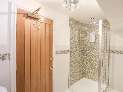 a bathroom with a shower and a wooden door at Bryn Ogwen in Bangor