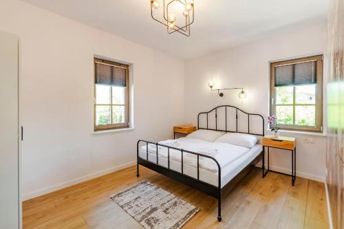 a bedroom with a bed and two windows at VacationClub - Stone Hill Apartament 5 in Szklarska Poręba