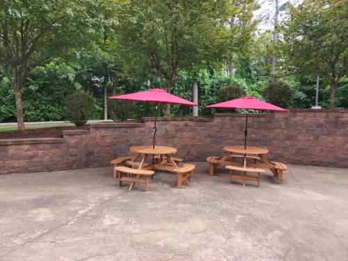 three picnic tables with red umbrellas in a park at La Quinta Inn & Suites by Wyndham Lake George in Lake George