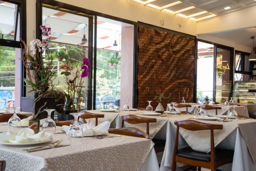 a restaurant with white tables and chairs and windows at Giraffe Boutique Hotel in Baguio