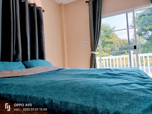 a bedroom with a bed and a large window at บ้านวาริ สะแกกรัง in Uthai Thani