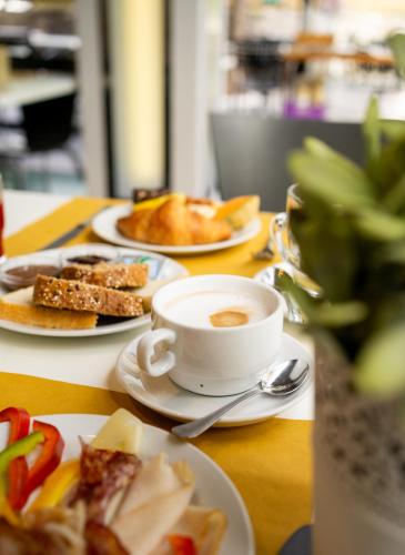 a table with plates of food and a cup of coffee at Hotel Rudy in Riva del Garda