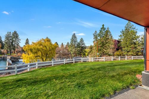 a fence next to a grassy field next to a river at Bend Riverside Condos Near Downtown Bend in Bend
