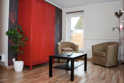 a living room with a table and two chairs and a red cabinet at B&B Die Alte Scheune in Manderfeld