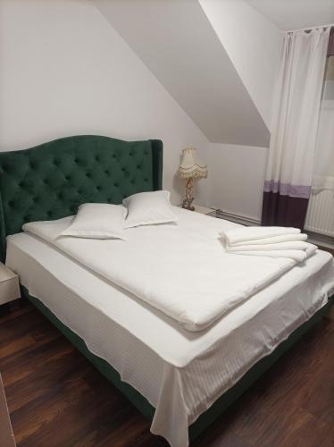 a bedroom with a large bed with a green headboard at Vila Alpina Olănești in Băile Olăneşti
