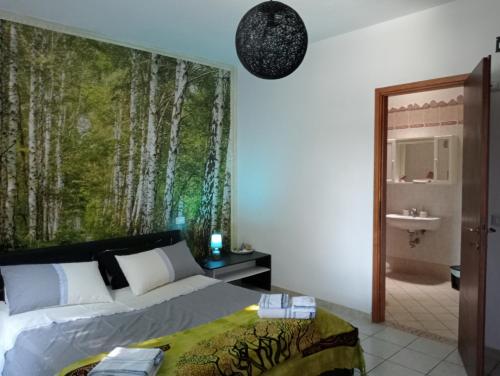 a bedroom with a bed and a wall mural of trees at La Mimosa in Porto Garibaldi