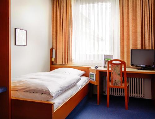 a bedroom with a bed and a desk with a television at Seligweiler Hotel & Restaurant in Ulm