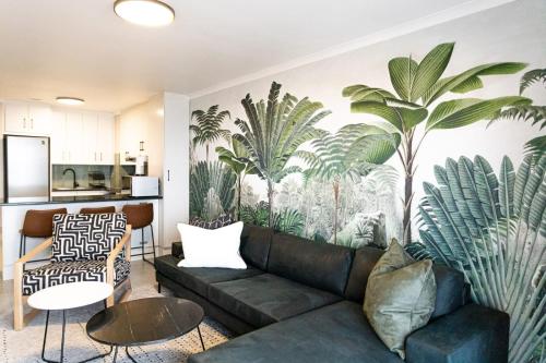 a living room with a couch and palm trees mural at Santos Seaview Apartment in Mossel Bay