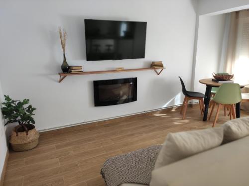 sala de estar con chimenea y TV en la pared en Apartamentos La Casa del Maestro en Alhama de Aragón