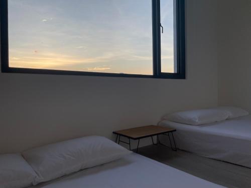 two beds in a room with a window and a table at Tino House 全新開幕 質感包棟民宿 in Yilan City