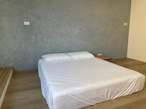a white bed in a room with a wall at Tino House 全新開幕 質感包棟民宿 in Yilan City