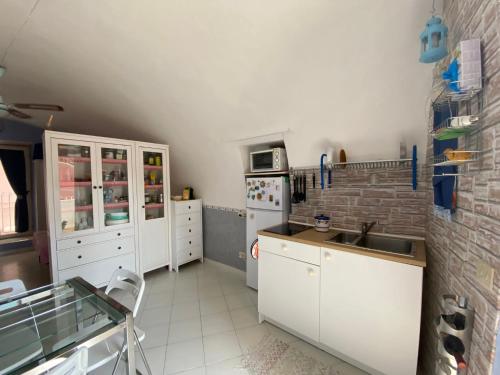 una cucina con armadietti bianchi e un muro di mattoni di La Graziella monolocale Procidano a Procida