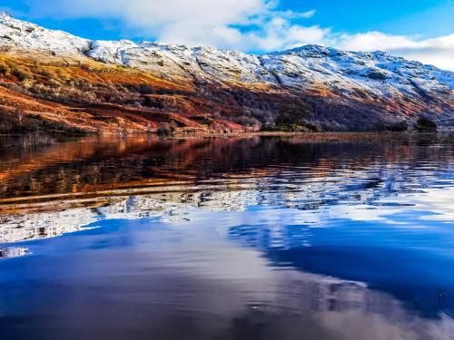 a reflection of a mountain in a body of water at Bonnie Banks Lodge Ardlui in Ardlui