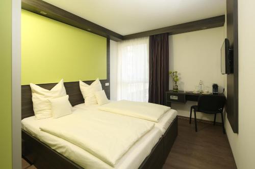 a bedroom with a large bed with a green wall at Economy-Hotel in Ulm