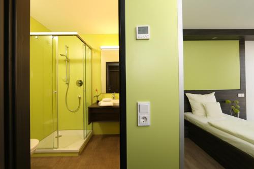 a bathroom with a shower and a bedroom with a bed at Economy-Hotel in Ulm
