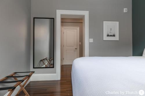 a bedroom with a white bed and a mirror at J Miller Flats by Thatch in Boston