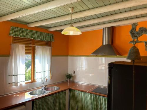cocina con paredes de color naranja, lavabo y ventana en El mirador de María, en Alcalá del Júcar