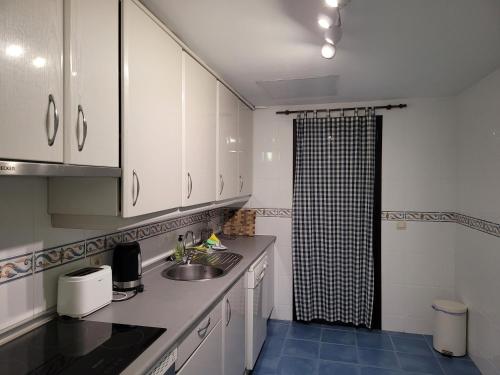 cocina con armarios blancos, lavabo y ducha en La Maestranza, Puerto Banus, en Marbella