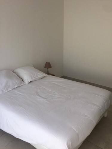 a white bed in a white room with a lamp at Maison neuve 2 min mer in Corbara