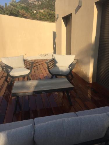 a patio with two chairs and a couch on a deck at Maison neuve 2 min mer in Corbara