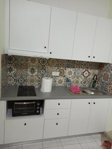 a kitchen with white cabinets and a sink at Christos beach apart in Kos Town