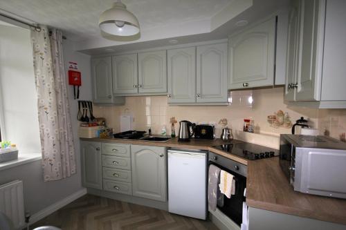 a kitchen with white cabinets and a stove top oven at Mullarts Church Apartments - The Glencorp Apartment in Knocknacarry