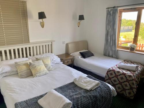 um quarto de hotel com duas camas e uma janela em The Milking Parlour em Aberystwyth