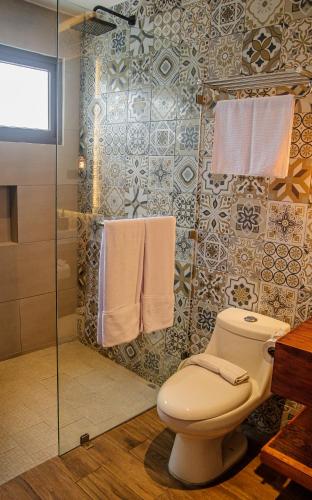 a bathroom with a toilet and a shower with towels at Hotel Las Camelias Inn by AHS in Antigua Guatemala